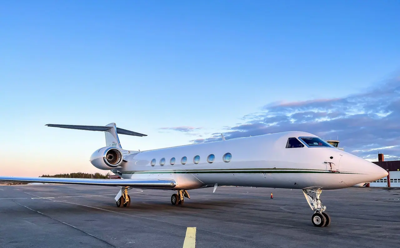 A white long-range business jet on the ramp beneath a blue sky