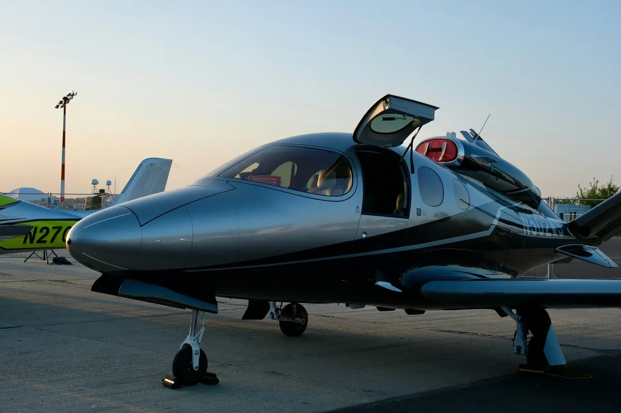 Close view of a sleek light jet with a polished, reflective paint finish on the ramp at dusk